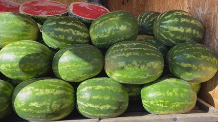 Fresh watermelons showing ripe red inside are stacked on wooden pallet