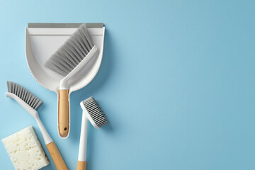 Household cleaning tools on a bright blue background. Top view dustpan, brush, sponge, and scrub...