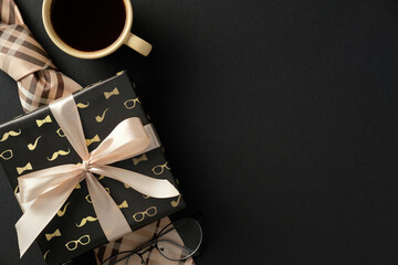Gift box with beige ribbon, coffee cup, plaid tie, and glasses on a black background. Perfect for...
