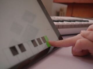 Child choosing correct answer on tablet music app hands close-up.
