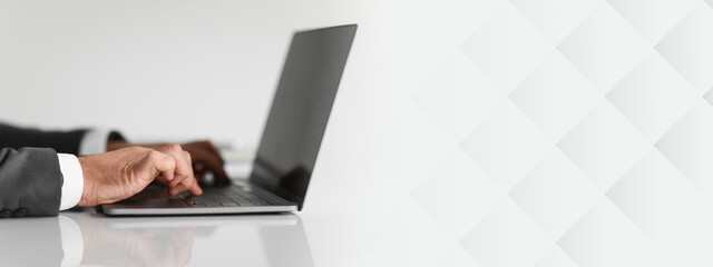 Close-up of caucasian businessman's hands typing on a laptop keyboard, showcasing details of his blue suit sleeve and professional work environment, cropped. Work, business