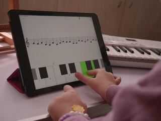 Child choosing correct answer on tablet music app hands close-up.