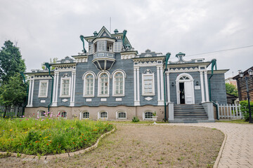 Fototapeta premium Traditional wooden dwelling featuring colorful floral landscaping near historic siberian street in irkutsk