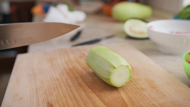 Chef Cuts Zucchini Vegetable On A Wooden Cutting Board In Restaurant Kitchen