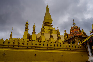 Naklejka premium Golden Stupa of Pha That Luang Temple in Vientiane, Laos under Overcast Sky – Iconic Buddhist Landmark and National Symbol