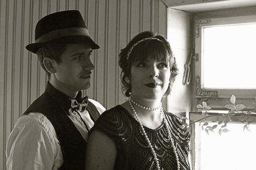 Ein Liebespaar im 20er Jahre Retro Style im Licht und Schatten vor einem Fenster