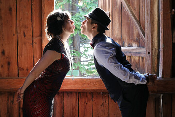 Ein Liebespaar im 20er Jahre Retro Style küssen sich vor einem Fenster