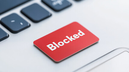 image depicts keyboard with red Blocked button, symbolizing restrictions digital communication. This represents how blocks can impact financial