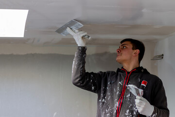 A man putting putty on a plasterboard ceiling. Putty for the joints of plasterboard sheets....