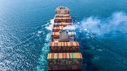 Aerial stern view of cargo ship carrying container and running for export goods from cargo yard...