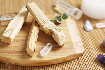 Palo santo sticks and gemstones on wicker table, closeup