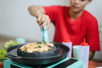 Man Grilling Chicken on a Pan at Korean BBQ Restaurant