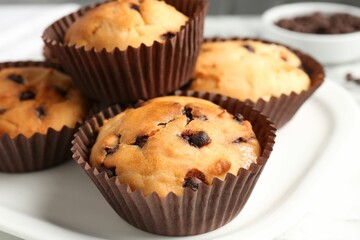 Delicious muffin with chocolate chips on plate, closeup