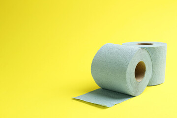 Light blue toilet paper rolls on yellow background, space for text