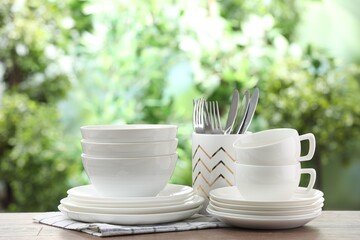 Clean dishware on wooden table against blurred background. Space for text