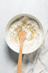 Overhead view of rolled out onion crackers dough being mixed in a white bowl, shallot cracker biscuit dough being mixed, process of making onion flatbread crackers