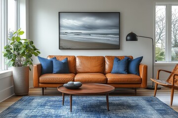 Fototapeta premium Mid-century modern living room with white walls, tan leather sofa, oversized beach print, vintage coffee table, blue accents, and natural lighting.