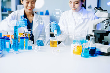 Two Asian female scientists conduct biochemical research using micro pipettes in a high-tech...