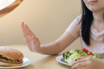 Beauty slim female body confuse hamburger. Woman in restaurant achieves weight loss goal for...