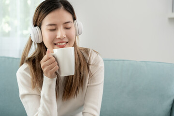Joyful young Asian women in wireless headphones sitting and enjoy music, having fun, listening to music, raising his arm, dancing to favorite song, enjoying cool soundtrack, happy life, recreation