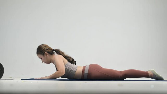 A woman in sportswear stretches her back on a fitness mat in the living room.