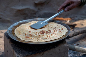 A village woman makes bread on the stove. cooking bread in clay stove , chula , makeing bread , roti , in village