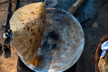 A village woman makes bread on the stove. cooking bread in clay stove , chula , makeing bread , roti , in village