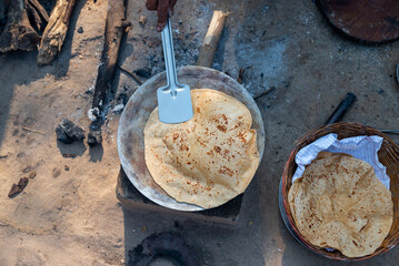 A village woman makes bread on the stove. cooking bread in clay stove , chula , makeing bread , roti , in village