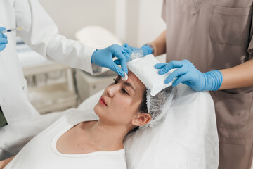 Asian woman receiving Assistant apply cold compresses to her face. Facial beauty injection...