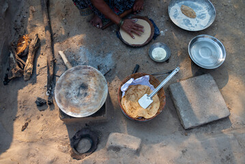 A village woman makes bread on the stove. cooking bread in clay stove , chula , makeing bread , roti , in village