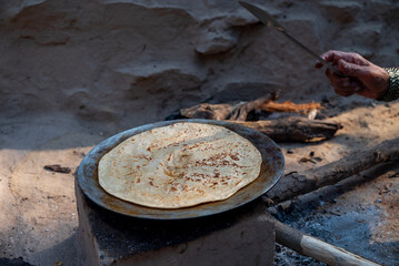 A village woman makes bread on the stove. cooking bread in clay stove , chula , makeing bread , roti , in village