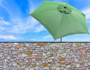 Parasol de jardin derrière muret de pierr