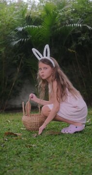 Festive Easter childrens game Egg hunt. The girl runs and jumps like a bunny in search of eggs, collects them in a basket and has fun against the backdrop of festive decorations. Family traditions.