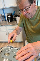 senior citizen fixing a toaster oven. in the kitchen