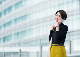 Fototapeta premium オフィス街を電話をしながら歩く30代日本人女性
