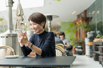 カフェでスマートフォンを見る30代日本人女性