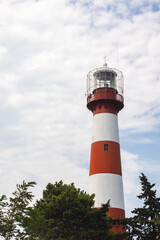 Red and white lighthouse on a background of blue sky with clouds in Poti, Georgia.
