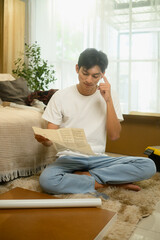 Young man reading an instruction manual while assembling furniture in a bright living room