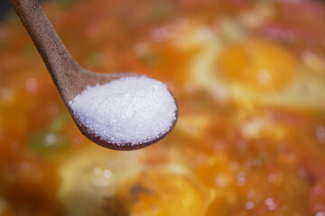 Cooking with salt added to a simmering dish in a kitchen