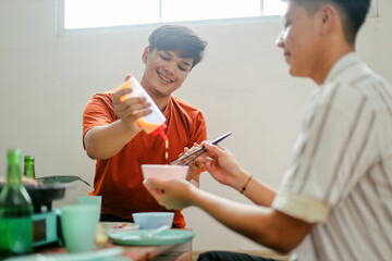 Young Man Helping Friend Adding Sauce On a Bowl At Barbeque Party