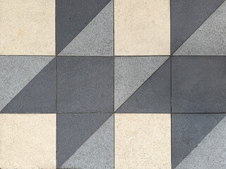Close up of geometrical tiles in square and triangular pattern. In white, light grey, and dark grey color. Seamless background texture.