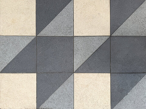 Close up of geometrical tiles in square and triangular pattern. In white, light grey, and dark grey color. Seamless background texture.