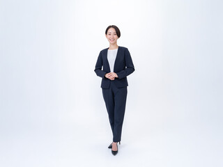 白背景で立つスーツを着た女性