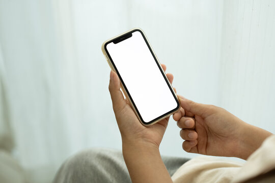 Close up shot of hands holding a modern smartphone with white screen sitting near a window - Powered by Adobe
