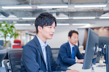オフィスでモニタに向かって働くビジネスマン