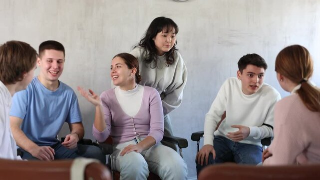 Group of cheerful carefree young students relaxing and chatting amicably during recess between lectures in auditorium. High quality 4k footage