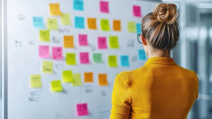 Data analytics concept. A person analyzing colorful sticky notes on a glass board, engaged in brainstorming or planning activities in a modern workspace.