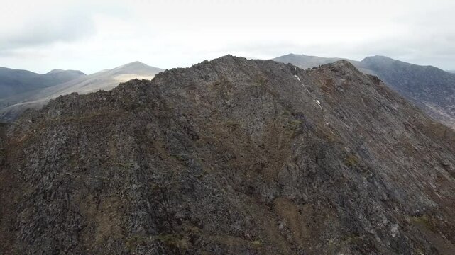 An aerial view of the rugged and jagged Crib Goch ridge in Snowdonia, Wales. This exposed mountain route is a popular yet challenging scramble, offering breathtaking views of the surrounding peaks.