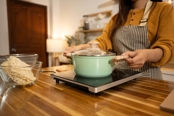 Young asian woman boiling water for instant noodles in a modern kitchen