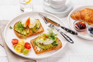 Breakfast with delicious avocado toasts and crispy croissant